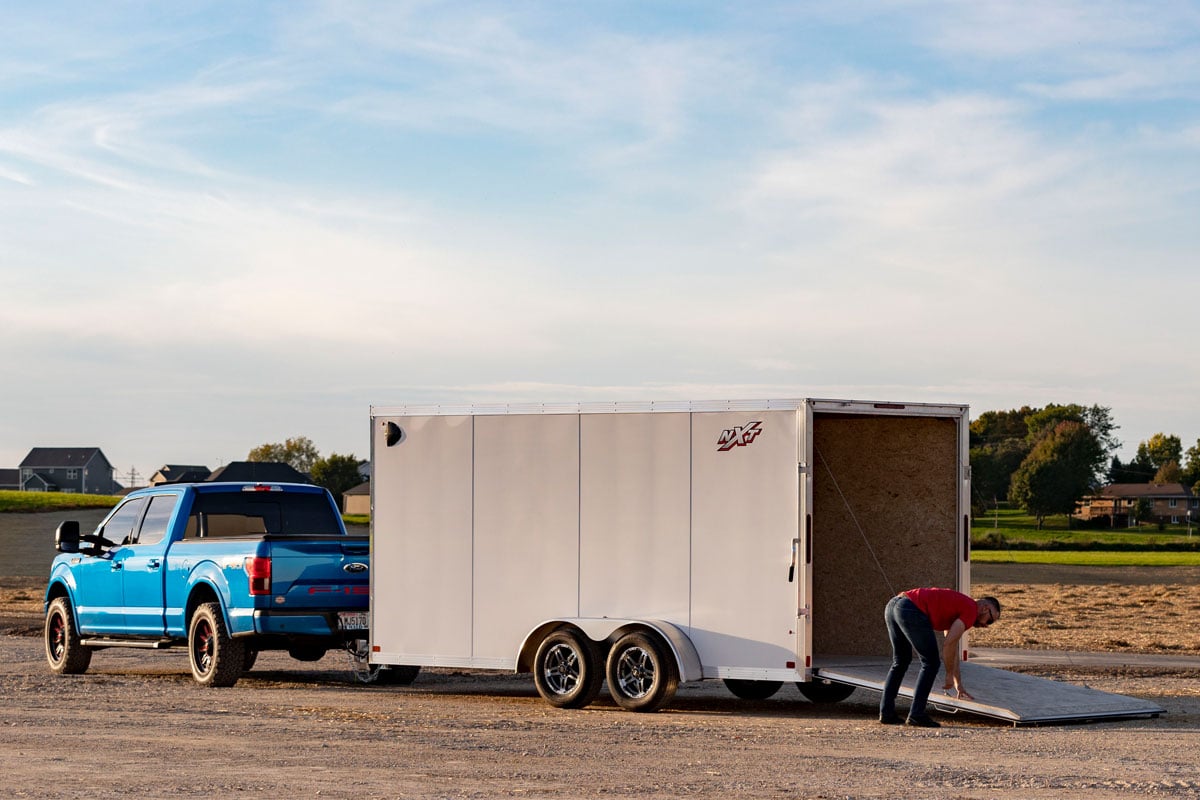 Blue Truck Parked With Triton Enclosed Snow Cargo NXT Series Trailer On Dirt Road