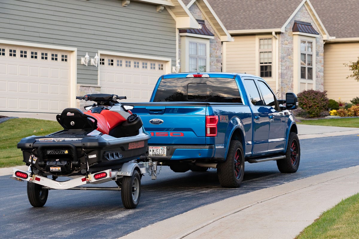 Blue Truck Towing Open Triton LT Series Through Neighborhood